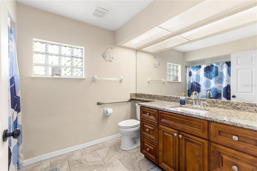 13481 Pullman Drive Spring Hill, FL 34609 - Photo 20 of 41 a bathroom with a granite countertop sink a toilet and a window