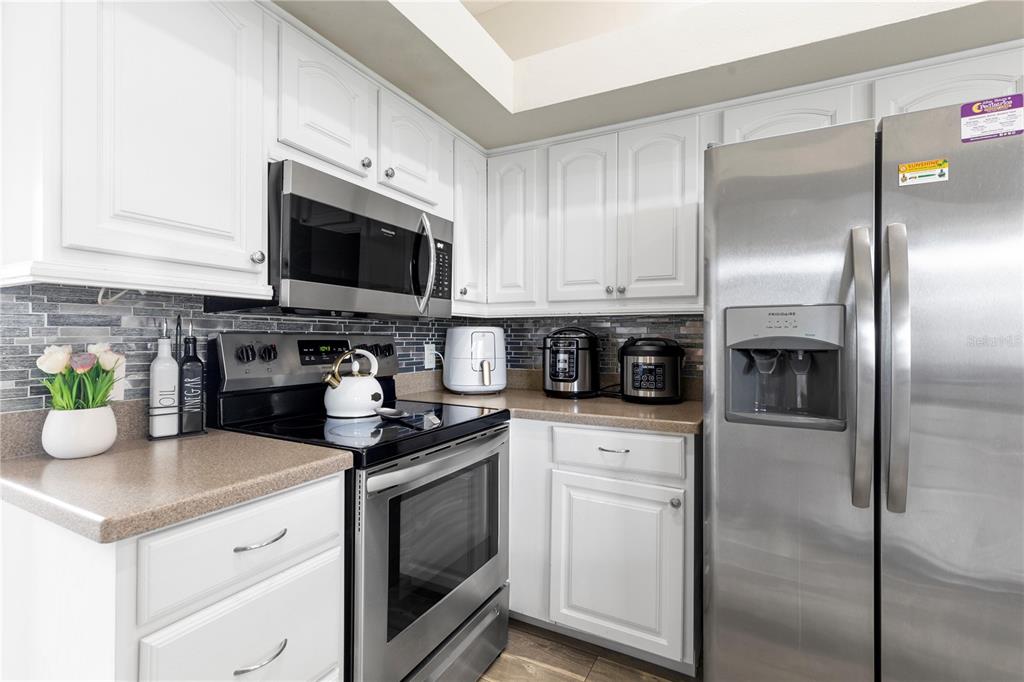 13481 Pullman Drive Spring Hill, FL 34609 - Photo 26 of 41 a kitchen with stainless steel appliances granite countertop a refrigerator a stove top oven a sink and dishwasher