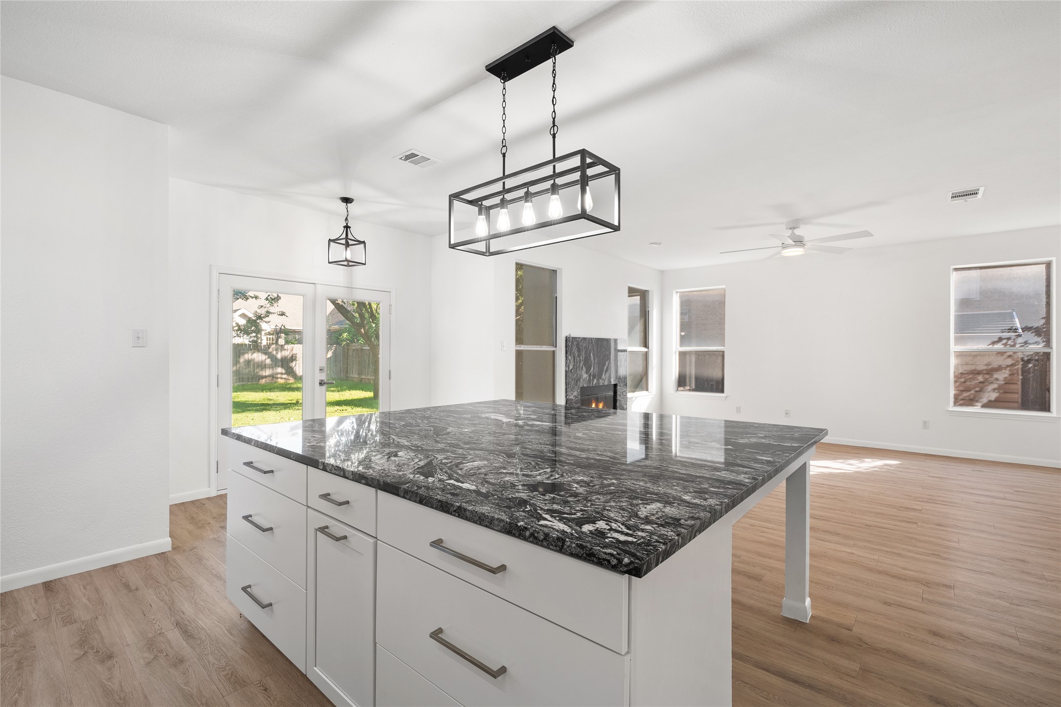 206 River Down Road Georgetown, TX 78628 - Photo 18 of 39 Kitchen island featuring a dark patterned countertop, white cabinetry, and brushed nickel hardware