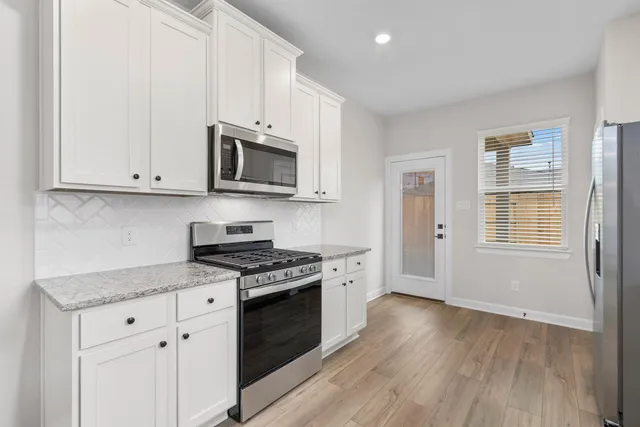 a kitchen with granite countertop wooden cabinets and a stove top oven