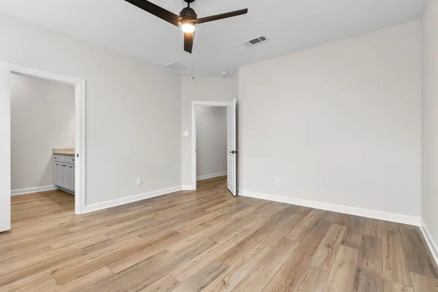 an empty room with wooden floor and a ceiling fan