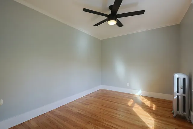 an empty room with wooden floor and a ceiling fan