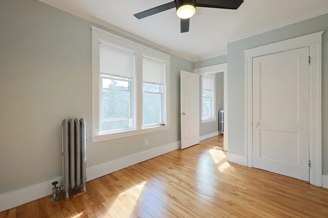 an empty room with wooden floor fan and windows