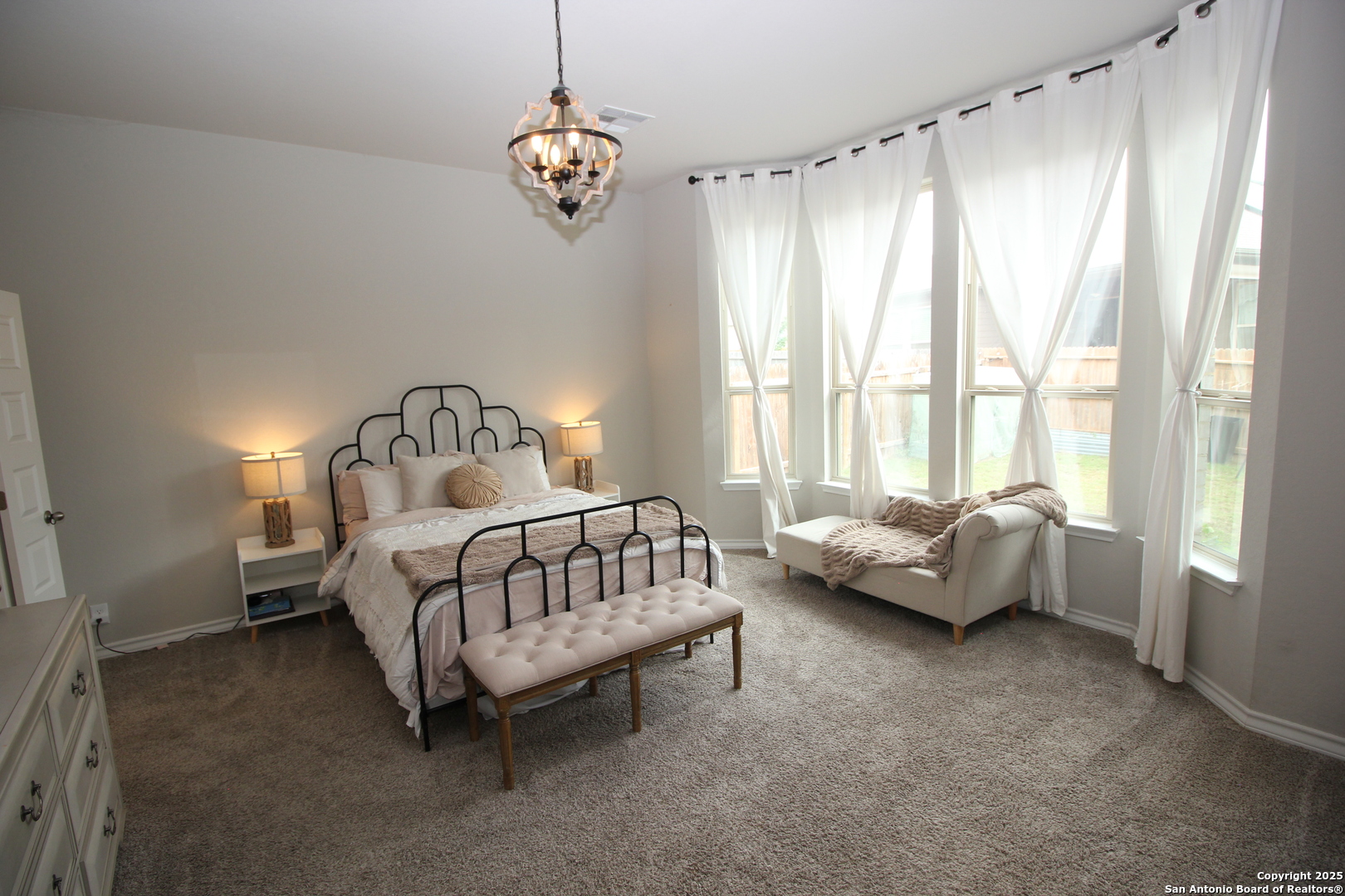 12228 Buckaroo Ranch San Antonio, TX 78254 - Photo 14 of 43 a bedroom with bed and a chandelier