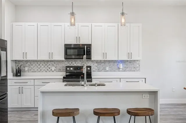 a kitchen with a refrigerator a stove a sink and white cabinets with wooden floor