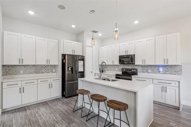 a kitchen with stainless steel appliances granite countertop a stove top oven a sink dishwasher a dining table and chairs with wooden floor