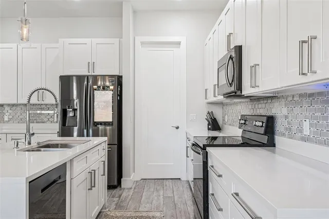 a large white kitchen with a refrigerator a stove and a sink