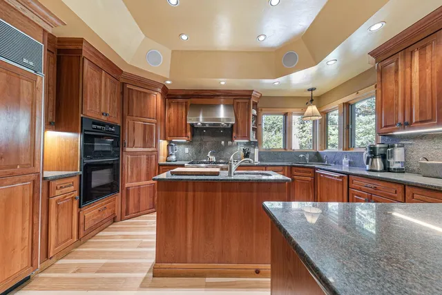 a large kitchen with stainless steel appliances kitchen island granite countertop a refrigerator a stove and a sink with wooden cabinets