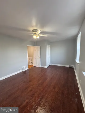 an empty room with chandelier fan and windows