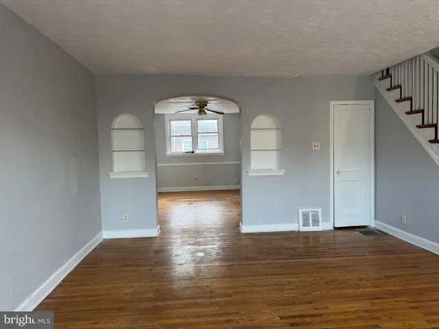 a view of empty room with wooden floor and fan