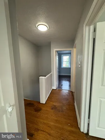 a view of a hallway view with wooden floor and a bathroom