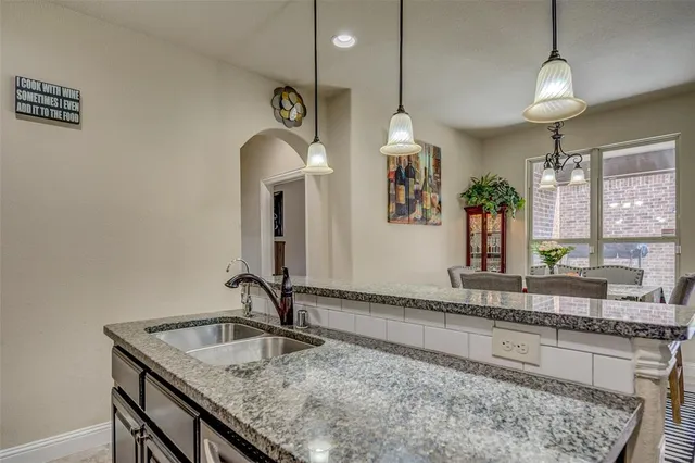 a kitchen with granite countertop a sink a counter space appliances and cabinets