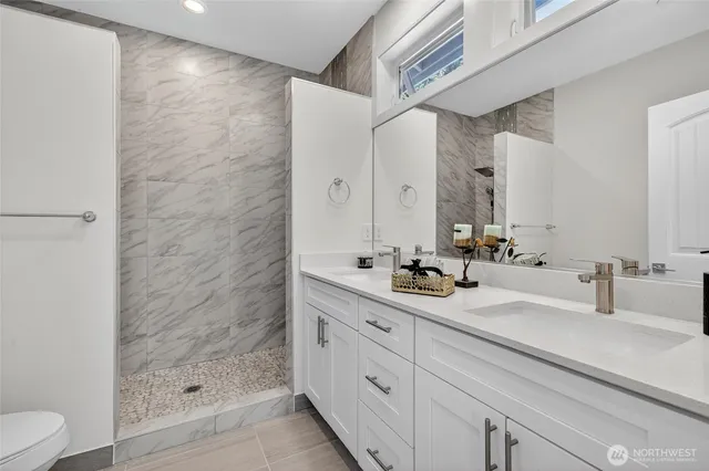 a bathroom with a double vanity sink toilet and shower