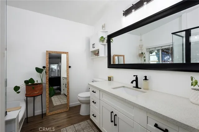 a living room with furniture kitchen view and a wooden floor