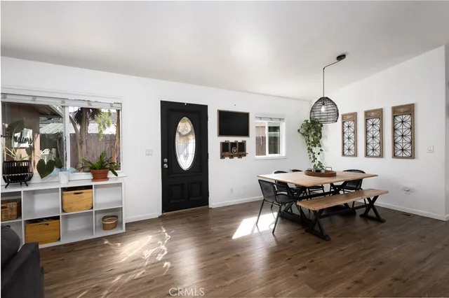 a kitchen with stainless steel appliances a refrigerator a stove a microwave oven a sink dishwasher and a dining table with wooden floor