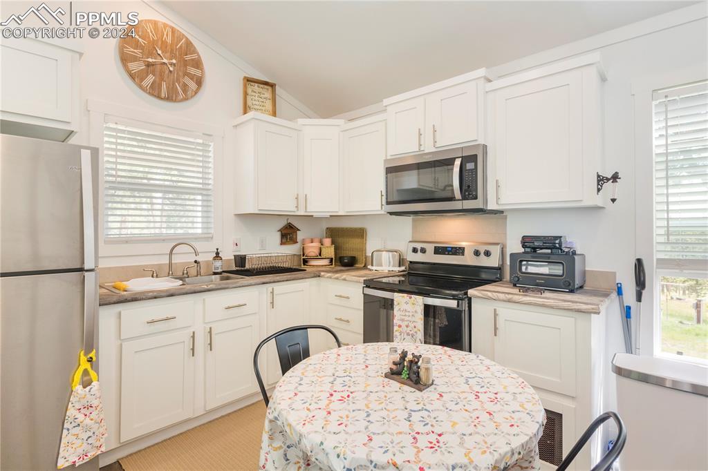 654 Tess Trace Road Guffey, CO 80820 - Photo 28 of 42 a kitchen with stainless steel appliances granite countertop a sink a stove a microwave cabinets and a window