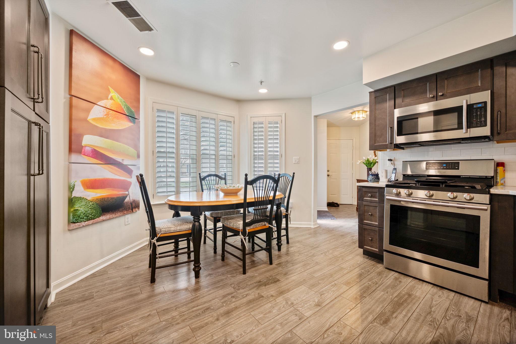 9136 Ruth Elder Lane, Unit 9136 Pikesville, MD 21208 - Photo 3 of 11 a kitchen with stainless steel appliances a stove a table and chairs