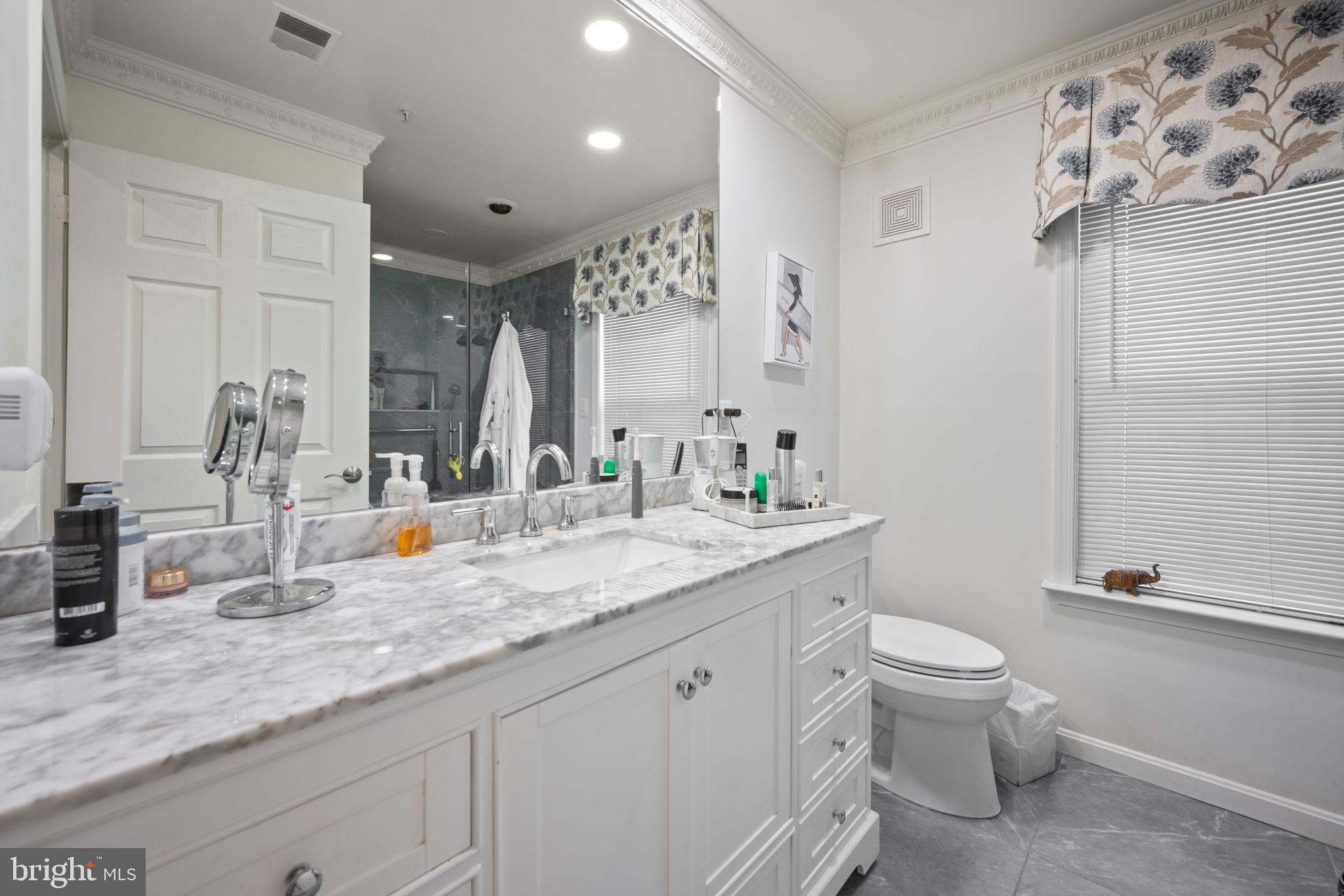 9136 Ruth Elder Lane, Unit 9136 Pikesville, MD 21208 - Photo 8 of 11 a bathroom with a granite countertop sink mirror vanity and toilet