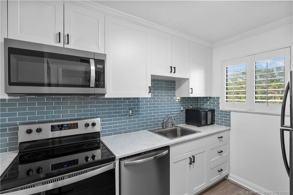5313 Southeast Miles Grant Road, Unit K209 Stuart, FL 34997 - Photo 12 of 34 a kitchen with appliances a sink and cabinets