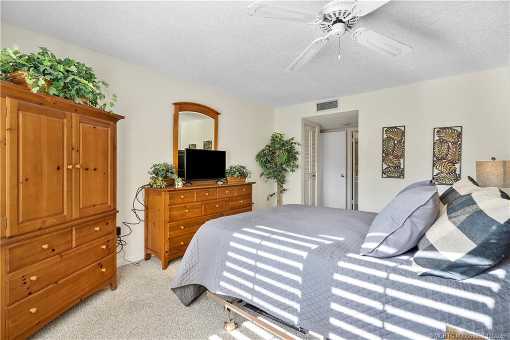 5313 Southeast Miles Grant Road, Unit K209 Stuart, FL 34997 - Photo 17 of 34 a bedroom with a bed a flat screen tv and dresser