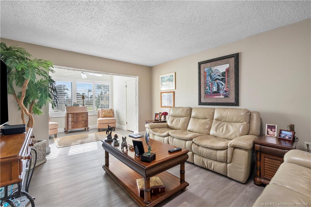 5313 Southeast Miles Grant Road, Unit K209 Stuart, FL 34997 - Photo 4 of 34 a living room with furniture a flat screen tv and a floor to ceiling window