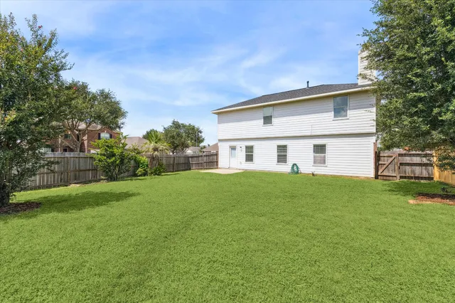 a view of a white house in front of a big yard with large trees