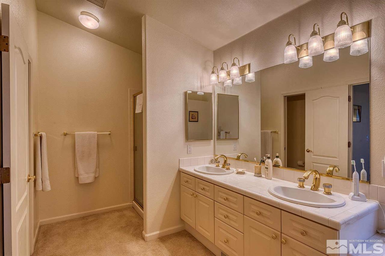 4811 East Creek Ridge Trail Reno, NV 89519 - Photo 16 of 25 a bathroom with a double vanity sink a mirror and a shower