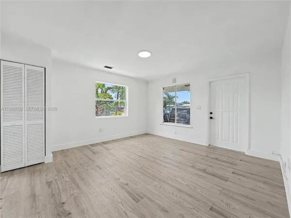 an empty room with wooden floor a ceiling fan and windows