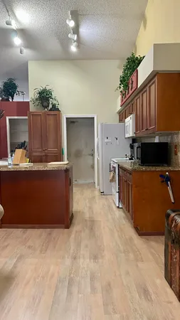 a kitchen with stainless steel appliances kitchen island granite countertop a refrigerator a stove and a wooden floors