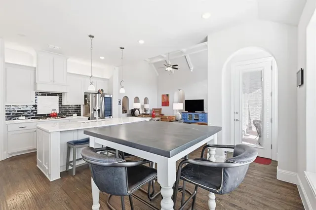 a room with stainless steel appliances kitchen island a table and chairs in it