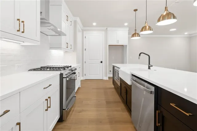 a kitchen with stainless steel appliances a sink a stove and a wooden floors