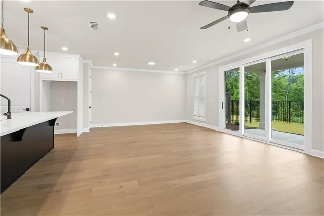 a view of an empty room with a window and kitchen view