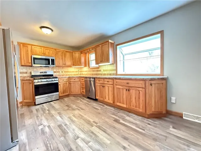 a kitchen with stainless steel appliances granite countertop a stove sink microwave and window