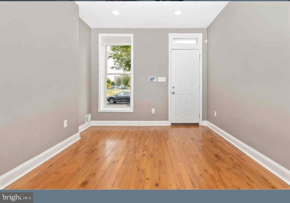 1112 Rutland Avenue Baltimore, MD 21213 - Photo 2 of 22 a view of an empty room with wooden floor and a window