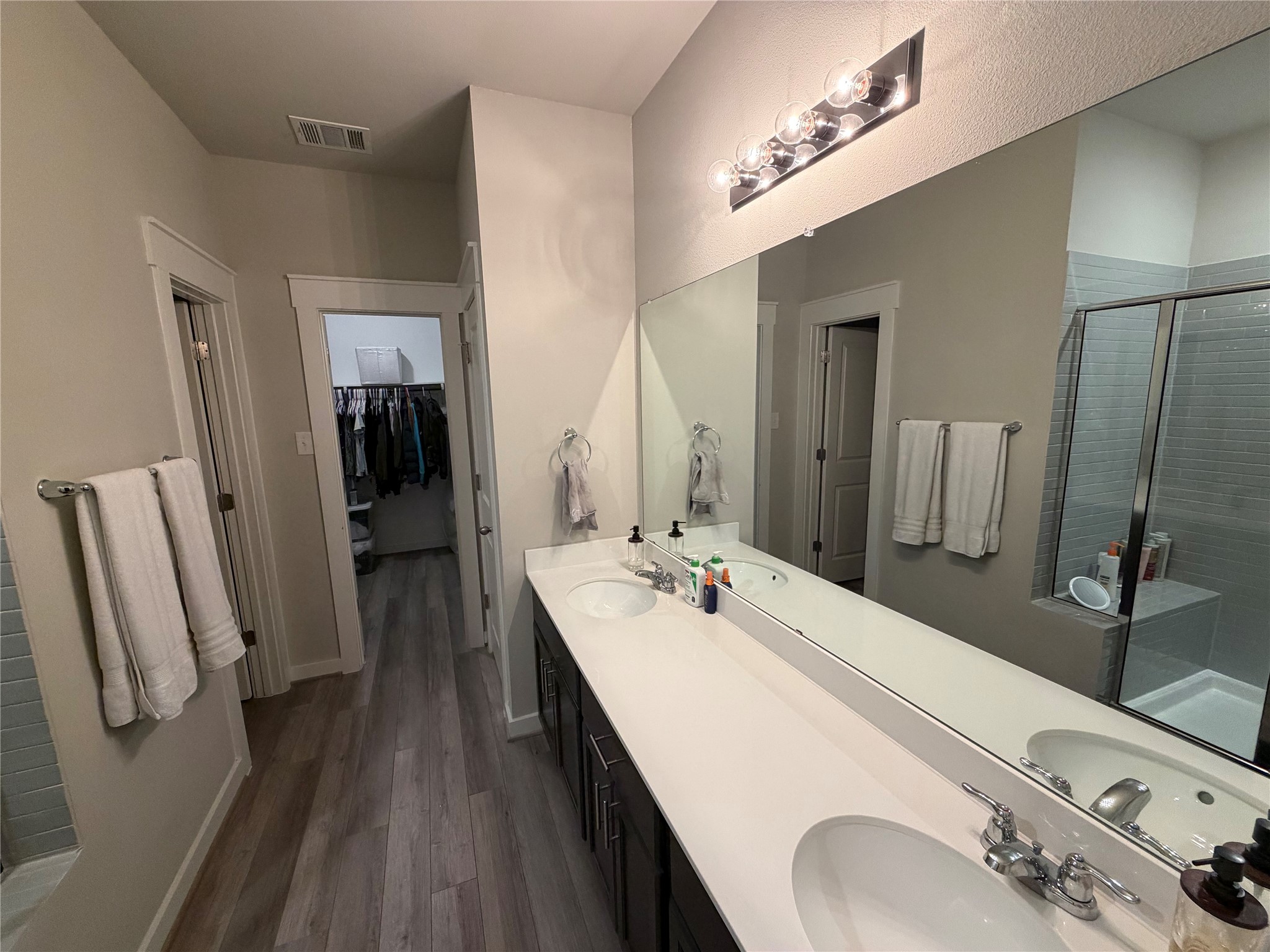 125 Threshing Road, Unit A Buda, TX 78610 - Photo 8 of 23 Bathroom featuring a shower stall, double vanity, dark wood-style flooring, and a walk in closet