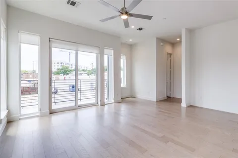 an empty room with wooden floor and windows with curtains