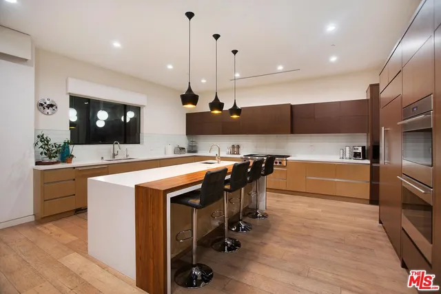 a kitchen with stainless steel appliances granite countertop a sink a stove and a wooden floors