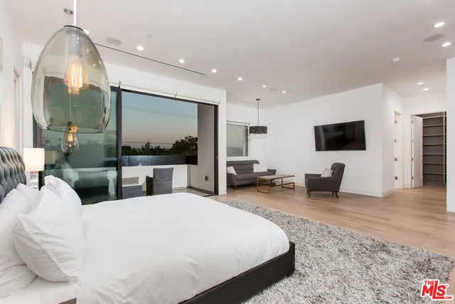 a large bedroom with bed a large window and flat screen tv