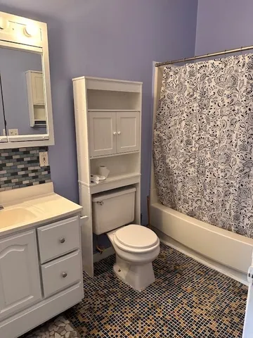 a bathroom with a granite countertop toilet a sink a mirror and shower