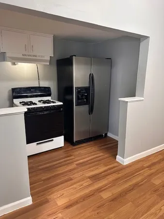 a kitchen with stainless steel appliances wooden floor and a refrigerator