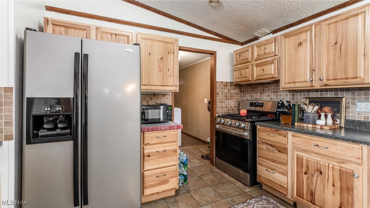 13306 Fairview Road Southeast Newark, OH 43056 - Photo 14 of 48 Kitchen with appliances with stainless steel finishes, a textured ceiling, light brown cabinets, vaulted ceiling, and light tile patterned floors