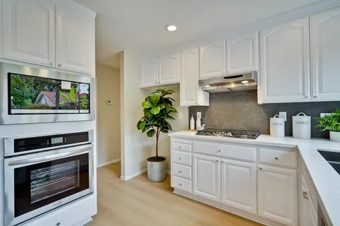 a kitchen with stainless steel appliances white cabinets and a stove top oven