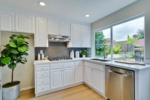 a living room with furniture a large window and wooden floors