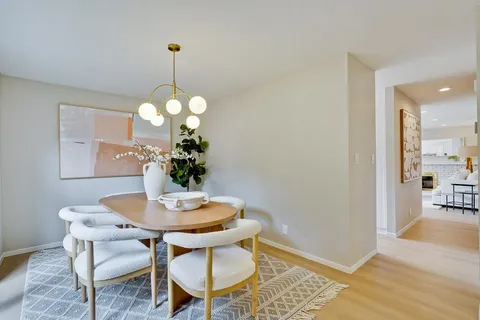 a dining room with wooden floor a chandelier a wooden table and chairs