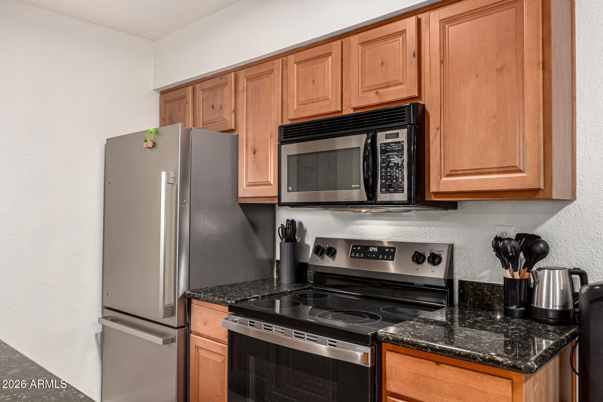 5877 North Granite Reef Road, Unit 1133 Scottsdale, AZ 85250 - Photo 11 of 33 a kitchen with granite countertop a refrigerator stove and microwave