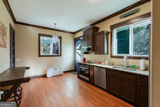 a kitchen with stainless steel appliances granite countertop a sink dishwasher stove and wooden floor