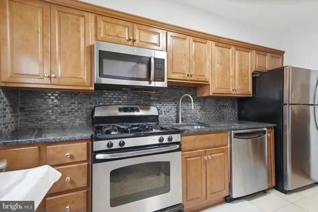 a kitchen with granite countertop cabinets stainless steel appliances and a counter space