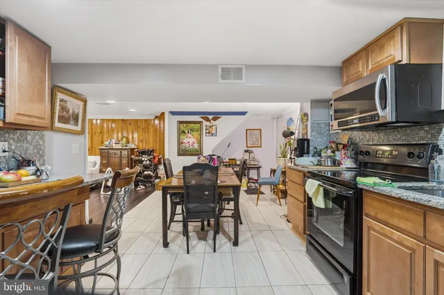 a open kitchen with stainless steel appliances granite countertop a stove top oven a sink a dining table and chairs
