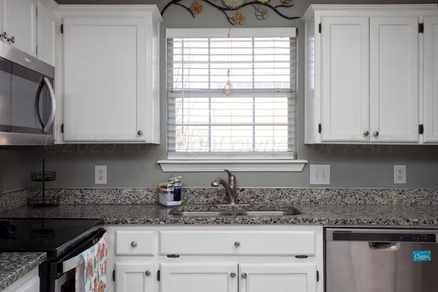 a kitchen with granite countertop white cabinets and window