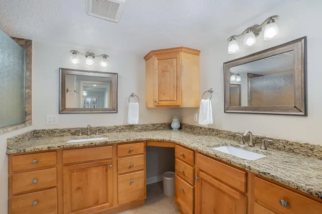 a bathroom with a granite countertop double vanity sink and mirror